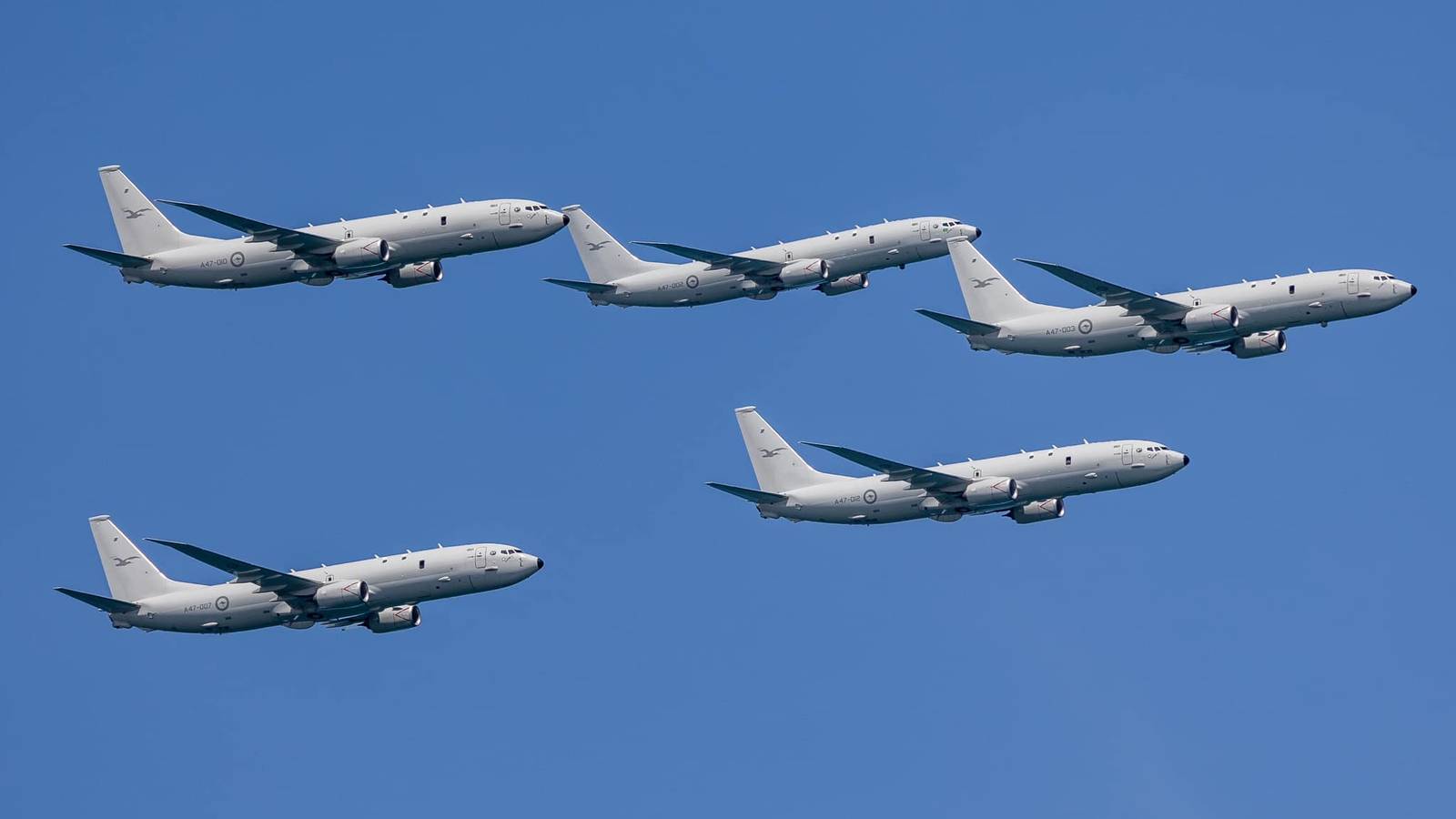 Five RAAF Poseidon maritime patrol aircraft fly in formation against a clear blue sky