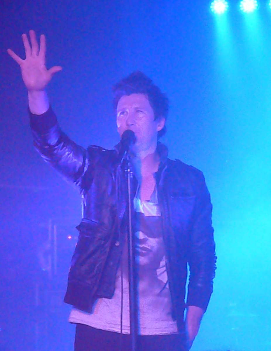 Anberlin singer Stephen Christian reaching up under blue stage light