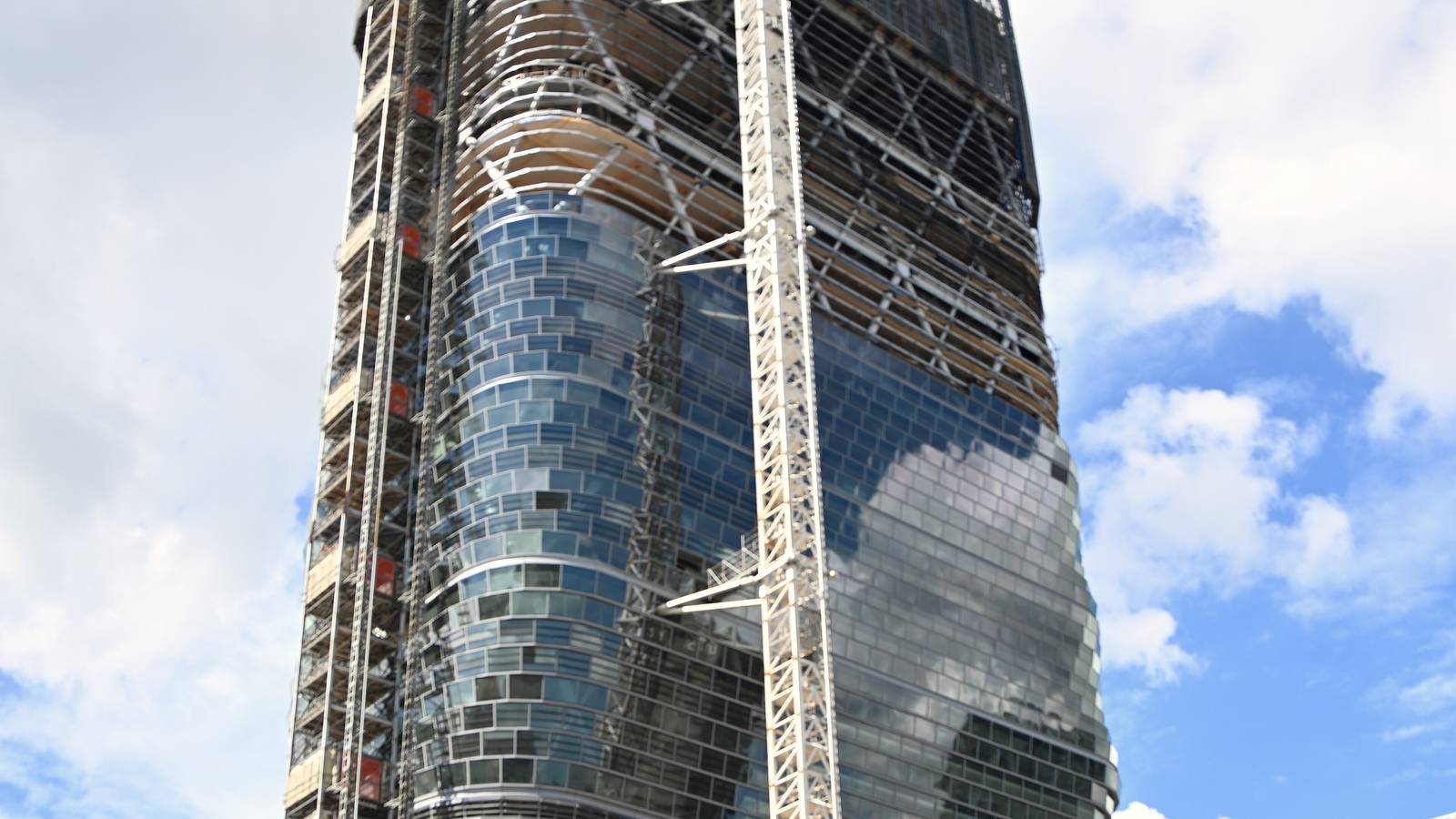 Atlassian Central, a glass and timber tower under construction near Central Station in Sydney, with a tower crane beside it