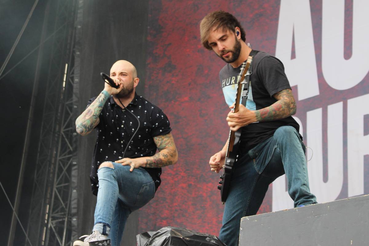 August Burns Red members playing guitar and singing on an outdoor stage