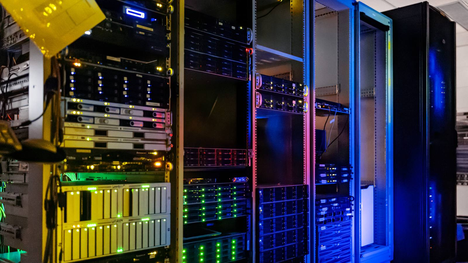 Rows of server racks with glowing green, red and blue status lights in a computer server room