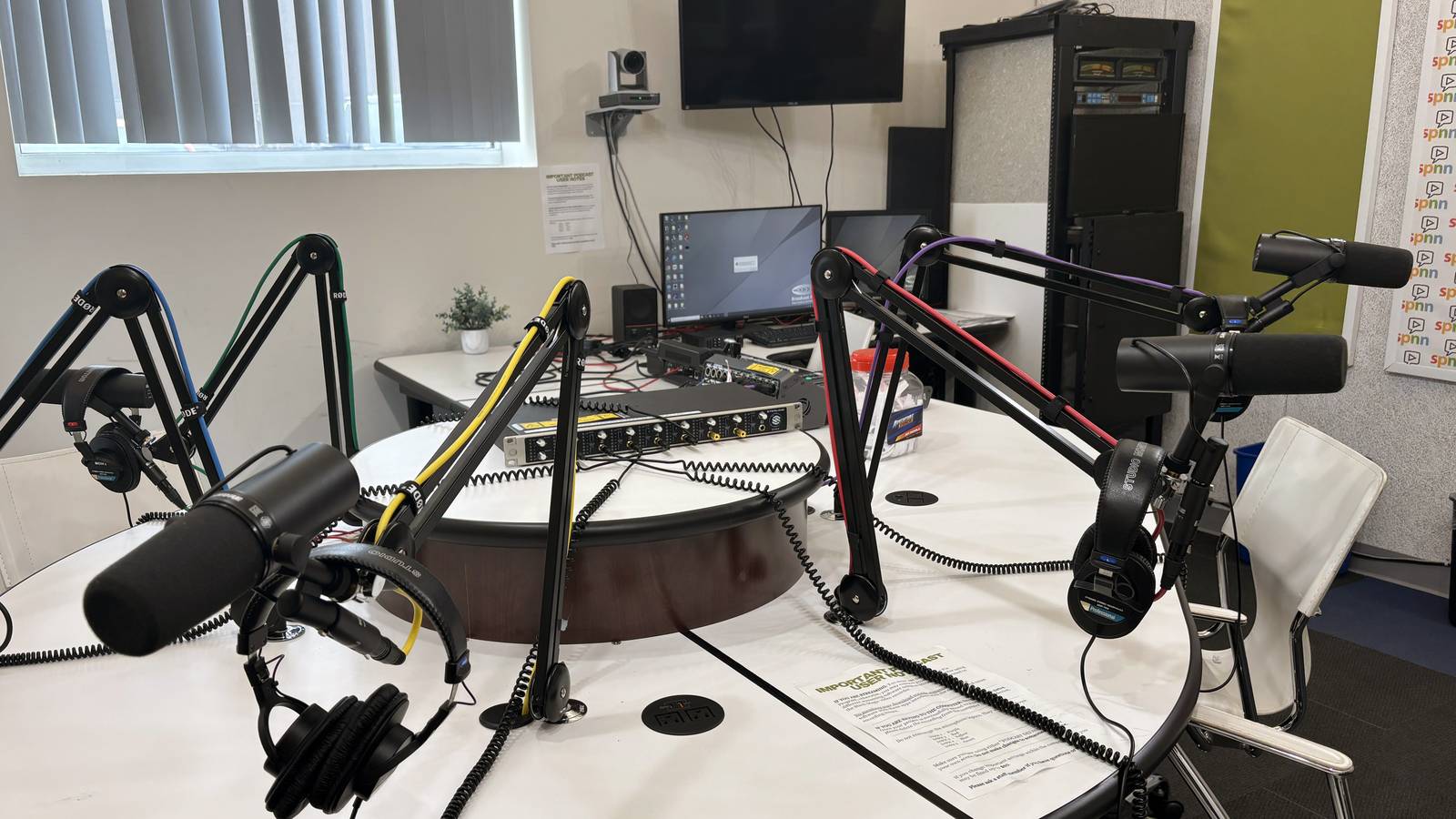 Several microphones on arms around a round table in a podcast recording studio