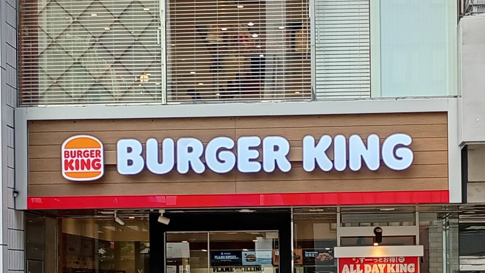 The Burger King sign above the glass shopfront of a Burger King restaurant on a street in Himeji, Japan