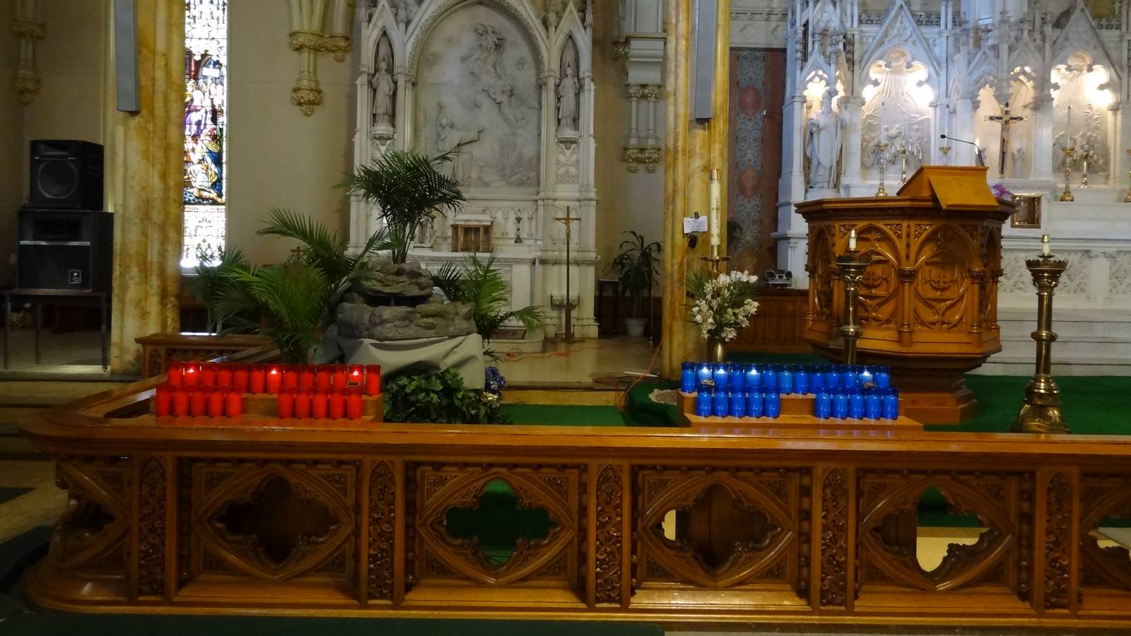 Rows of red and blue votive candles before an altar inside St Patrick Church in Lowell, Massachusetts