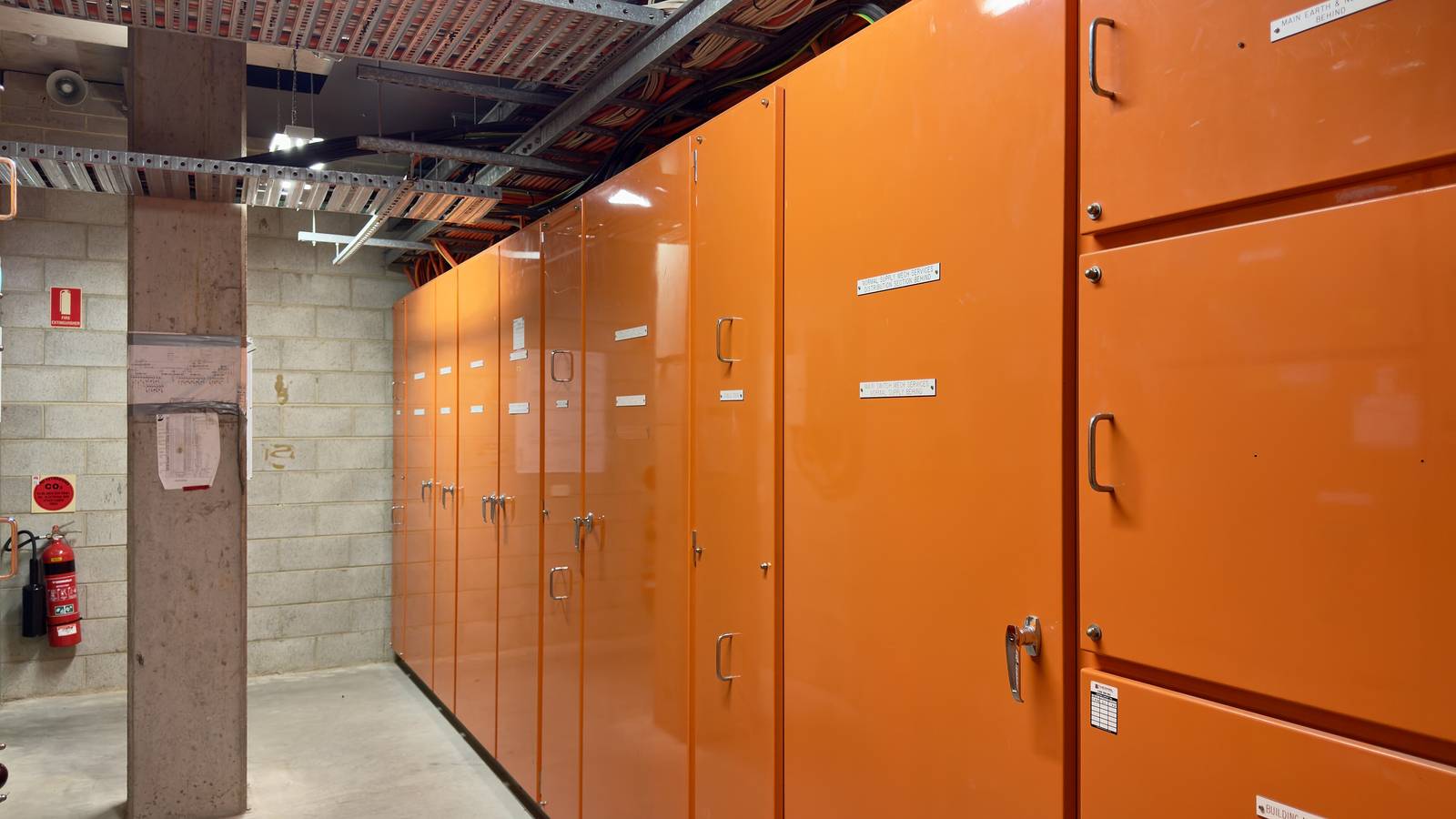 A row of orange main switchboard cabinets in a building's electrical switch room