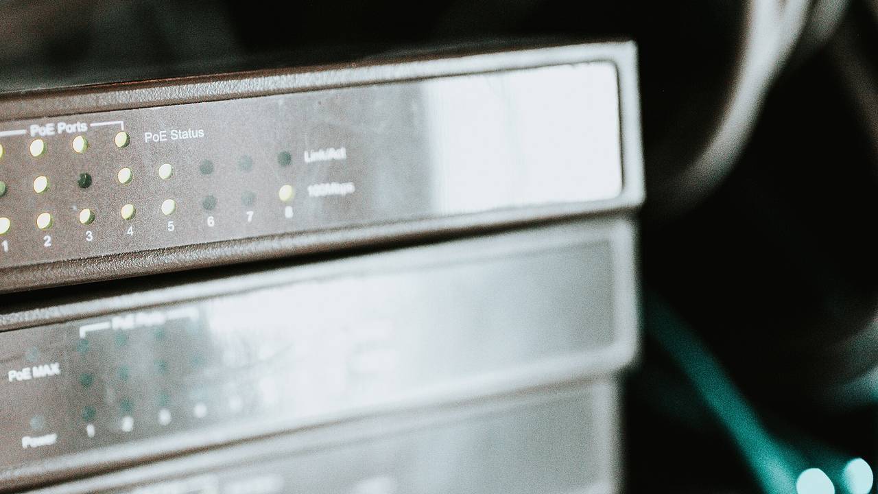 Stacked desktop network switches in a rack, with port status lights lit on the top switch