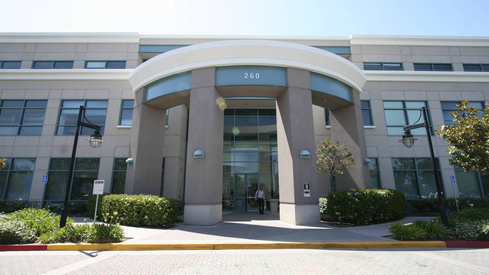 The curved canopy entrance of Building 9 on Cisco's main campus in San Jose with lawns and trees