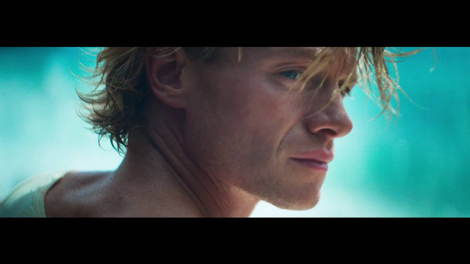 A blond man in close up against a turquoise background, in a frame from an official Clayface TV spot