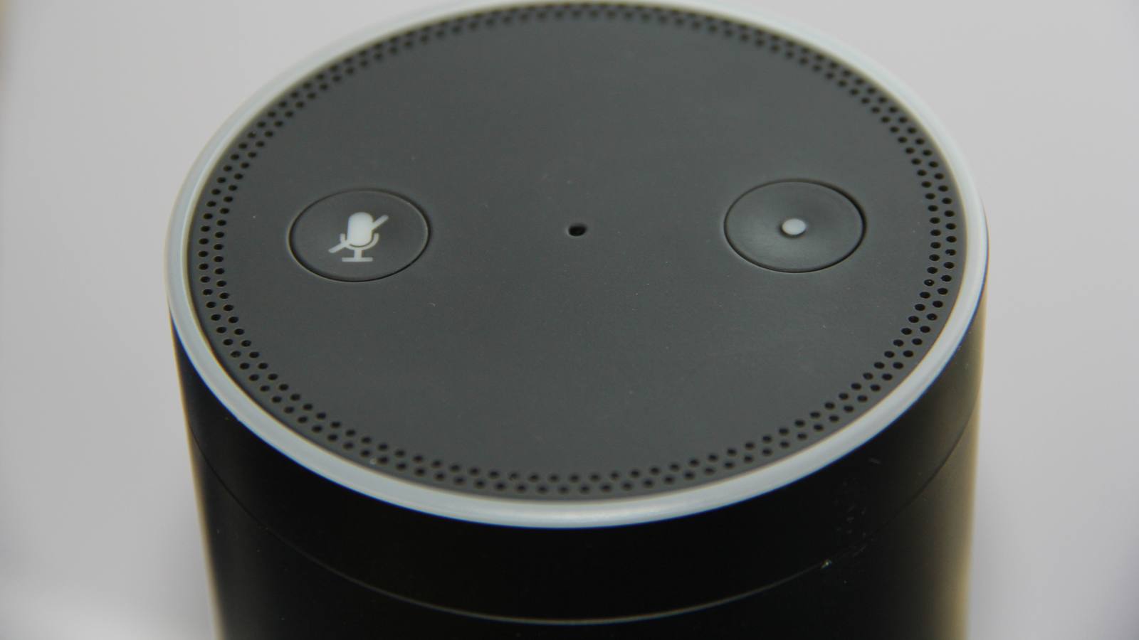 The top of a black Amazon Echo smart speaker showing its microphone off button, action button and speaker holes