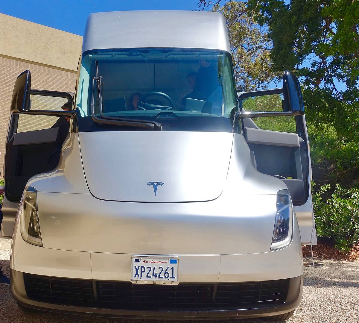 A silver Tesla Semi seen head-on with both cab doors open