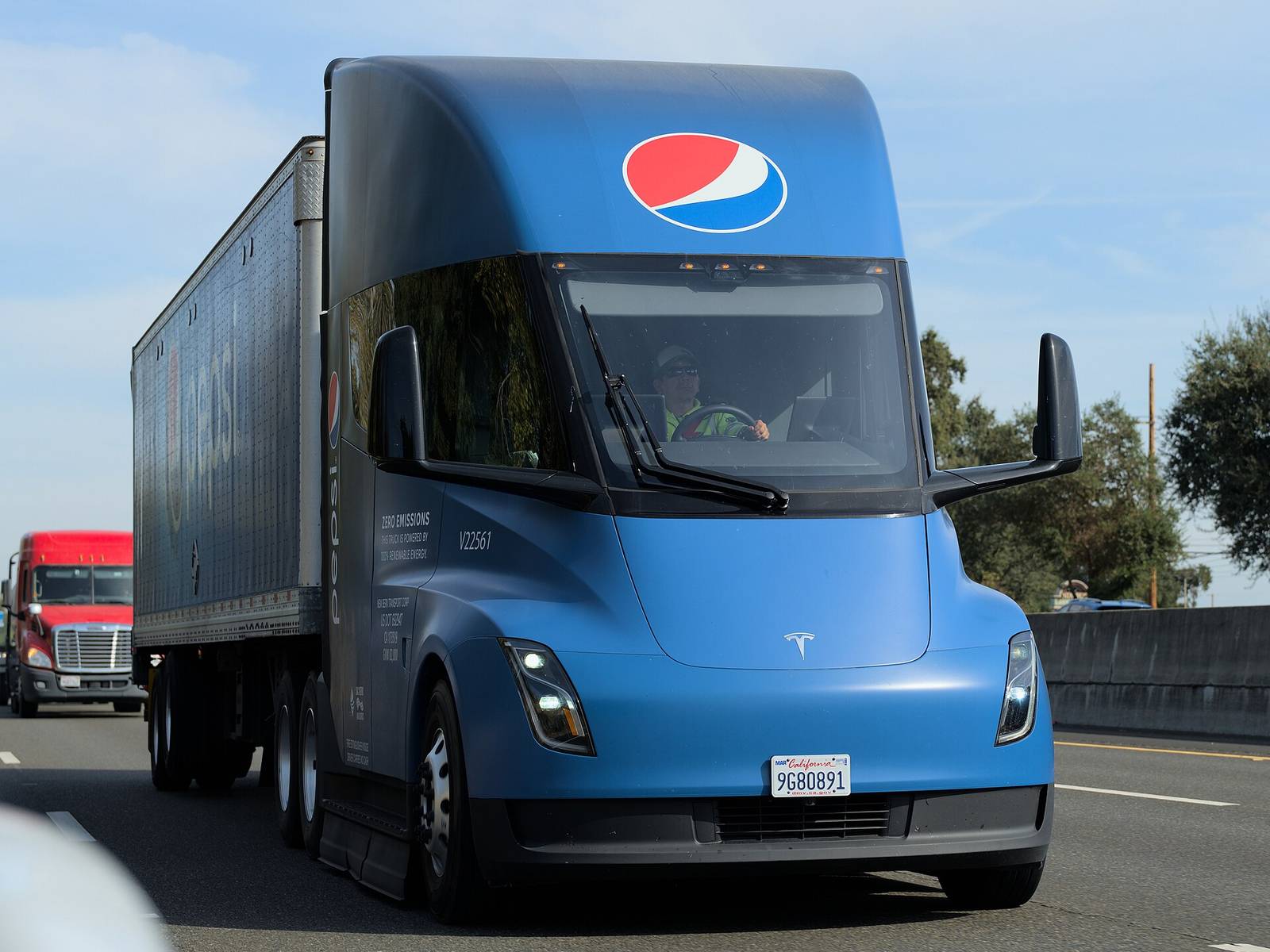 A blue PepsiCo Tesla Semi pulling a trailer on a highway