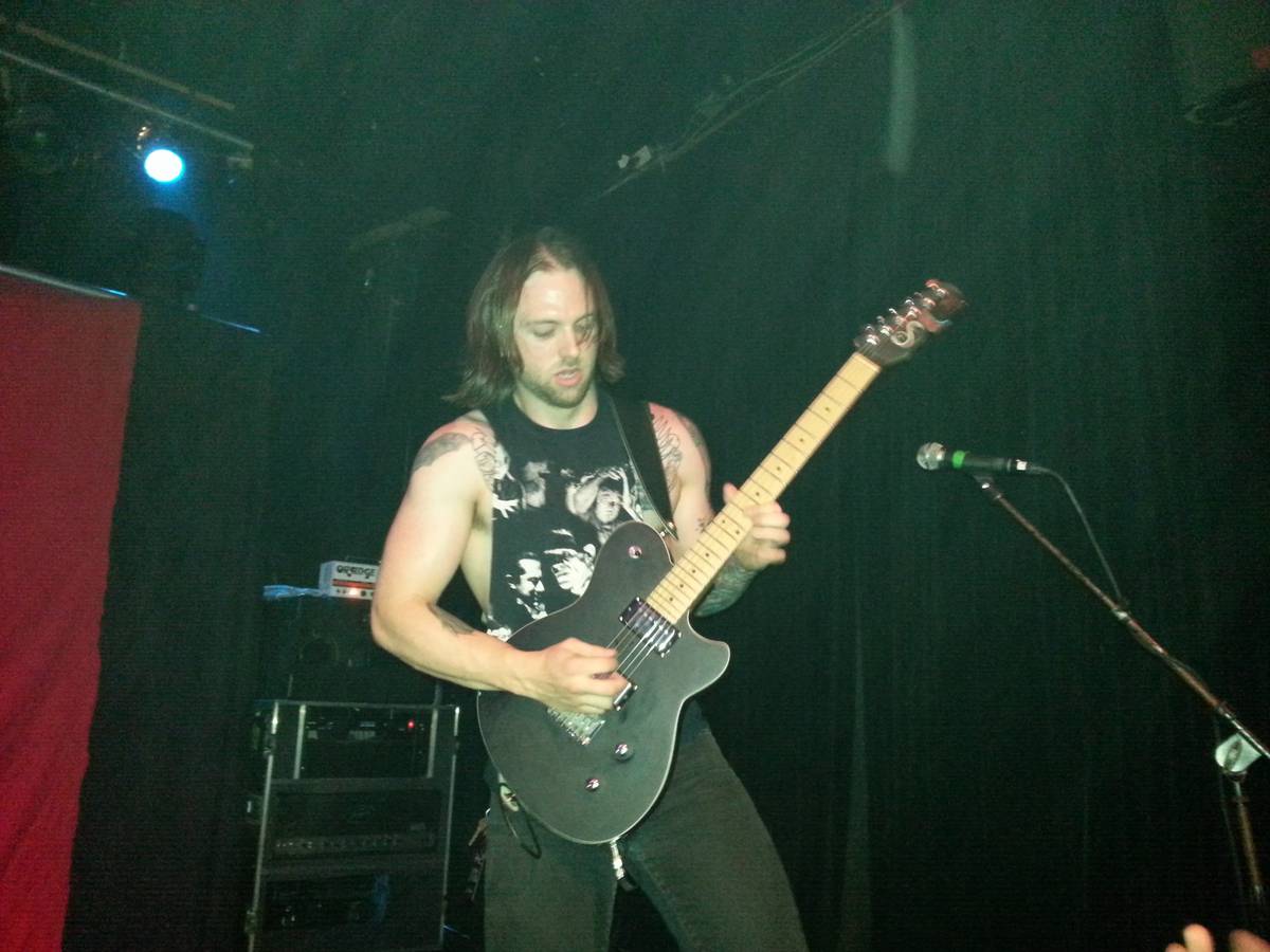 Demon Hunter guitarist Patrick Judge playing on a dark stage