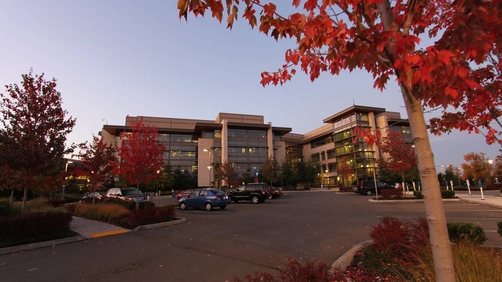 Low office buildings on Microsoft's West Campus in Redmond behind a car park and autumn trees