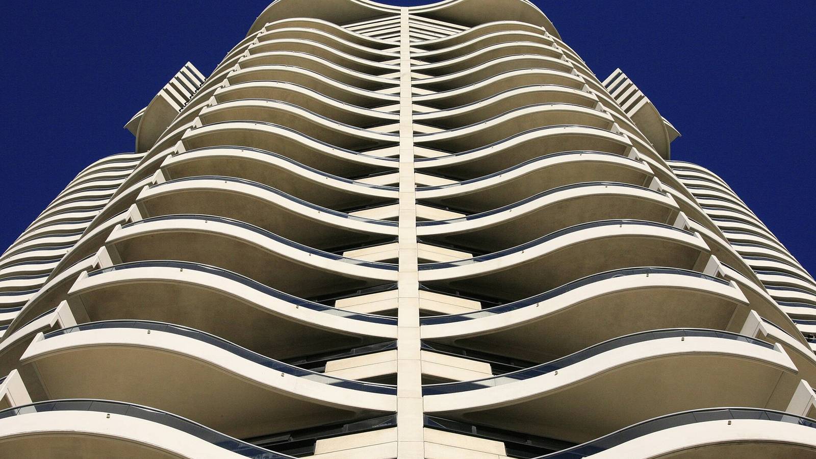 Curved balconies of a Sydney apartment tower against a blue sky