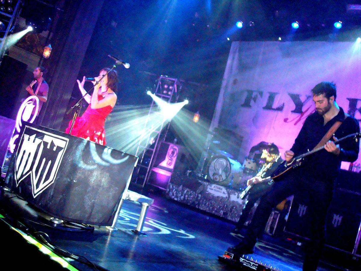 Flyleaf on stage with singer Lacey Sturm in front of a lit band backdrop