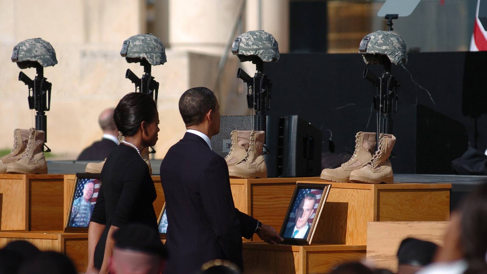 Barack and Michelle Obama walk past helmets, boots and photographs honoring the 13 Fort Hood victims at a 2009 memorial