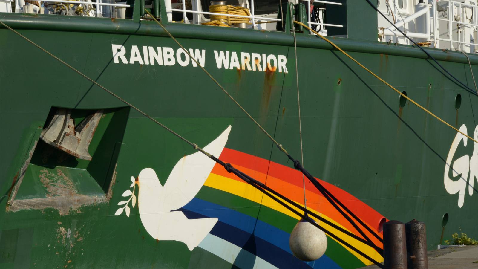 The hull of Greenpeace's ship Rainbow Warrior, with its name, a white dove and a rainbow painted on green