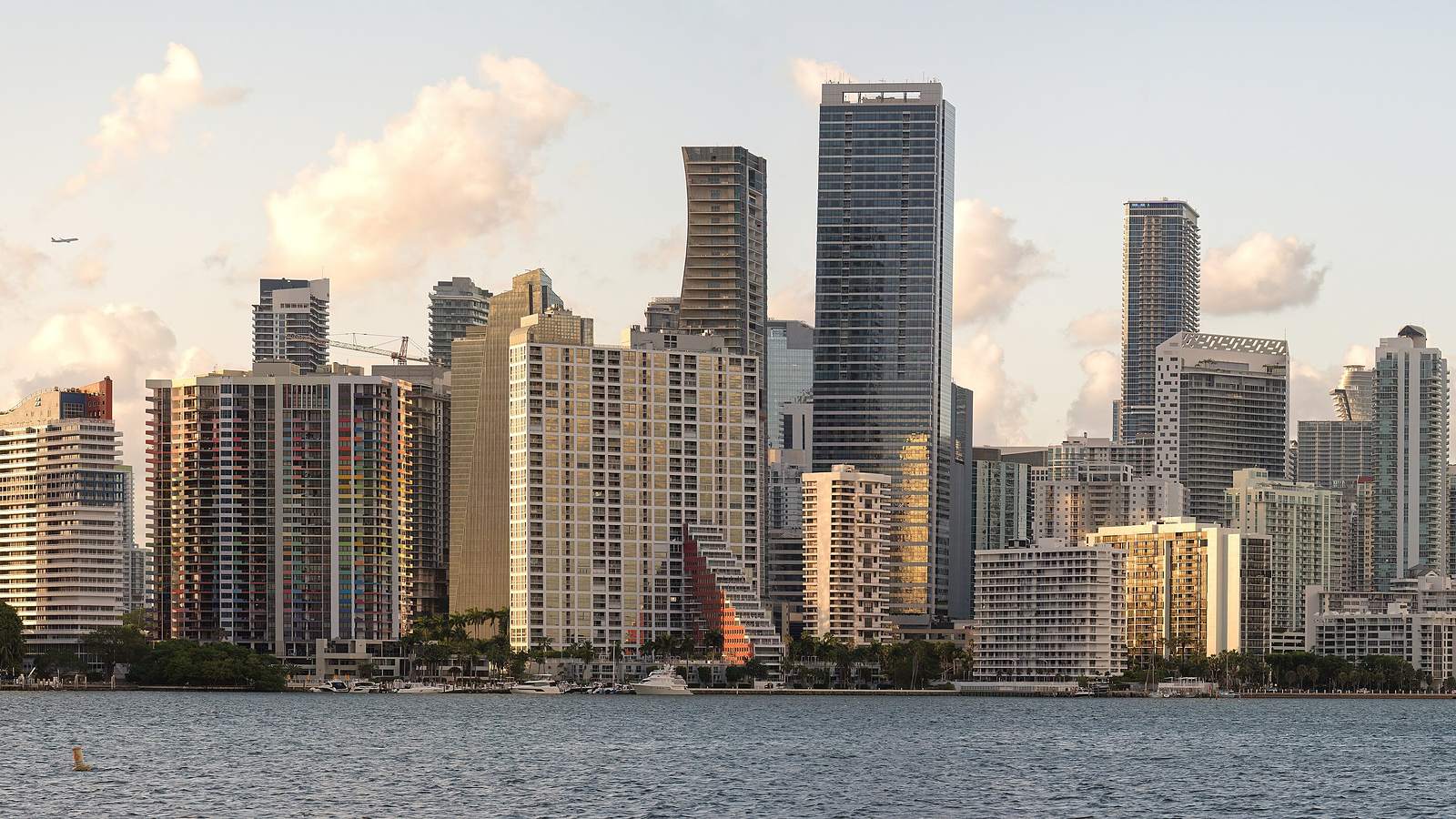 The Miami skyline of high-rise towers seen across the water under scattered evening cloud