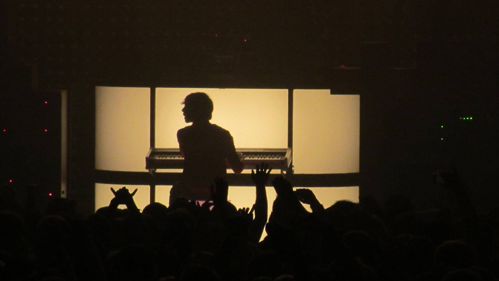 Xavier de Rosnay of Justice silhouetted at a keyboard on a lit stage above a crowd