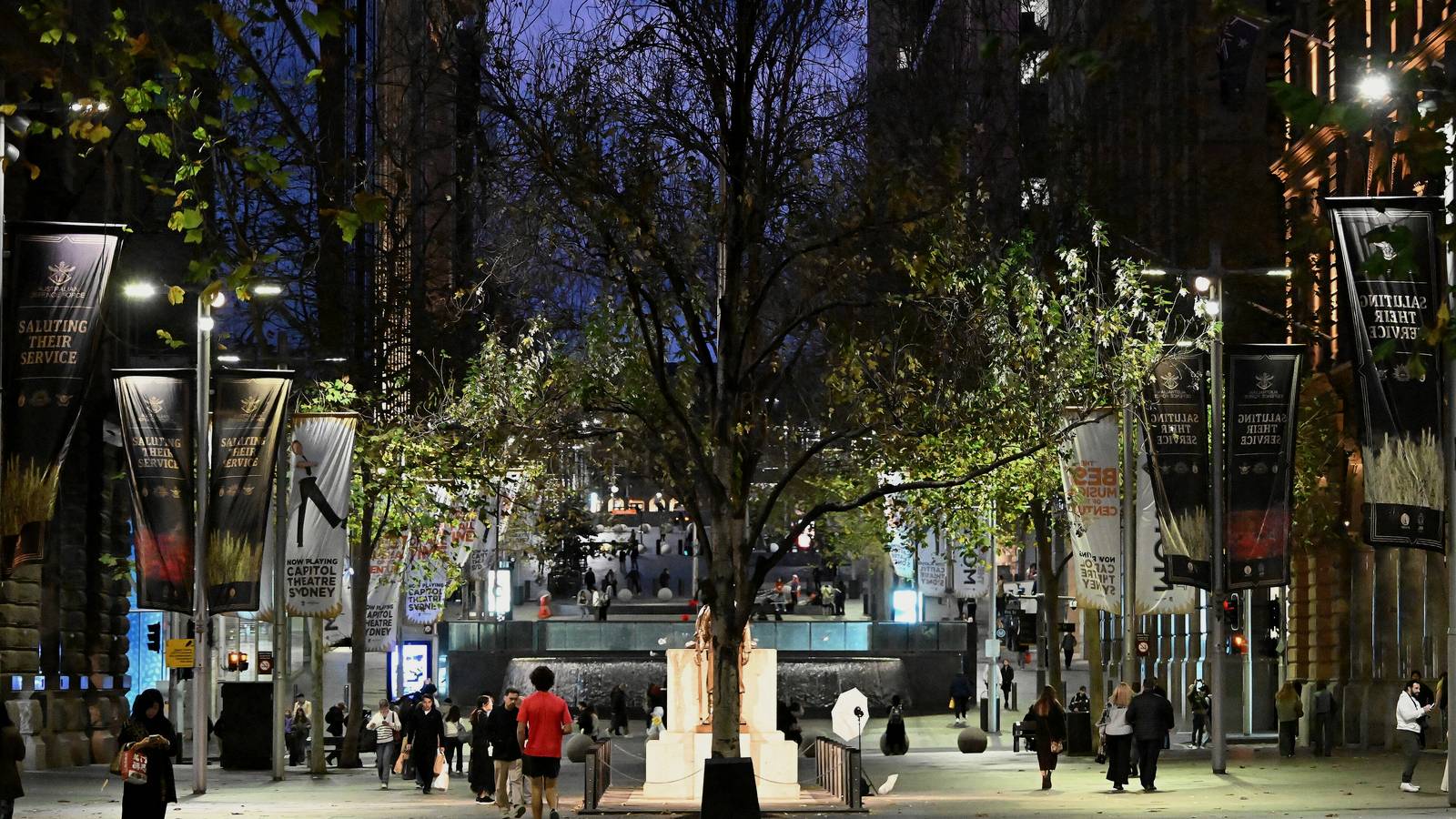 Martin Place, Sydney, at dusk, with pedestrians, street lights and banners along the pedestrian mall