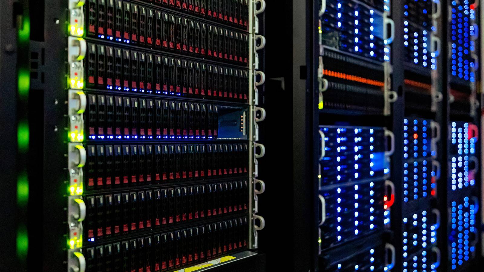 Rows of rack mounted servers with blue and green lights in a server room