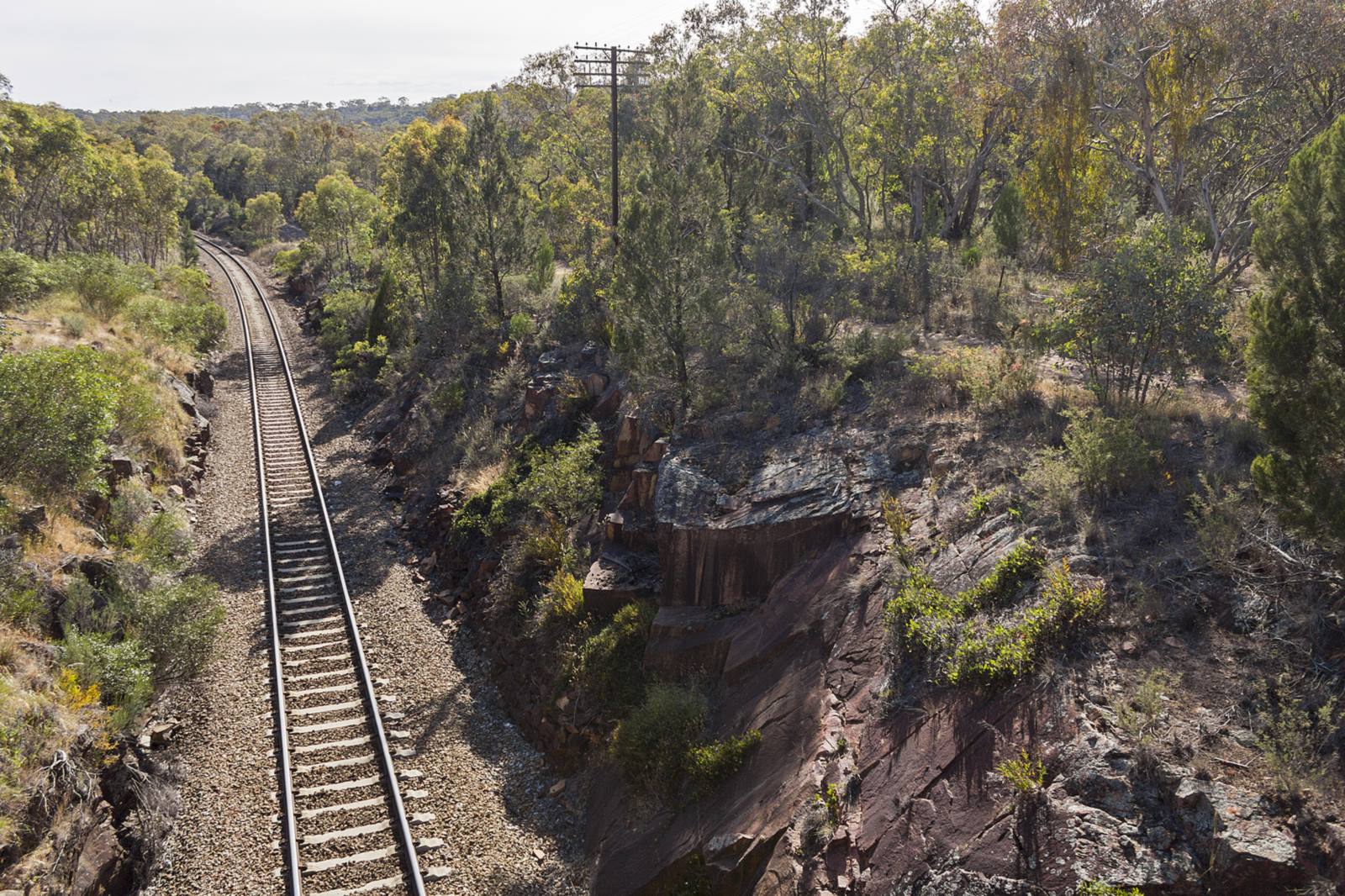 A single freight track curves through a rocky cutting on the Bethungra Spiral near Bethungra, NSW