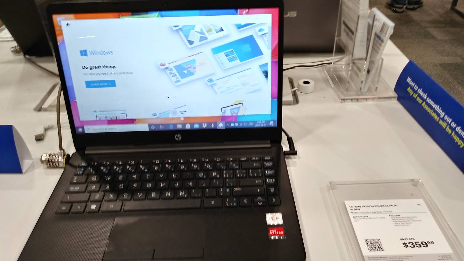 An HP laptop running Windows 10 on a store display table, with its price card beside it