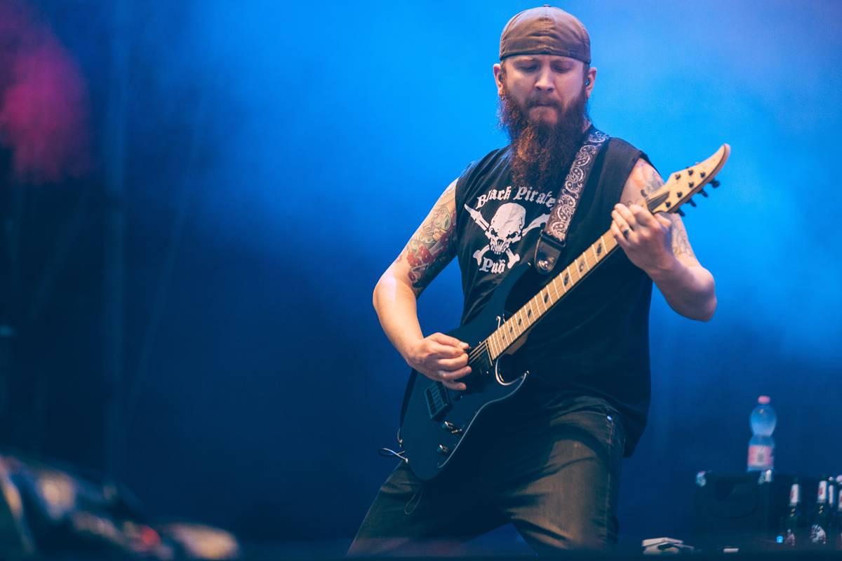 Killswitch Engage guitarist playing under blue stage light
