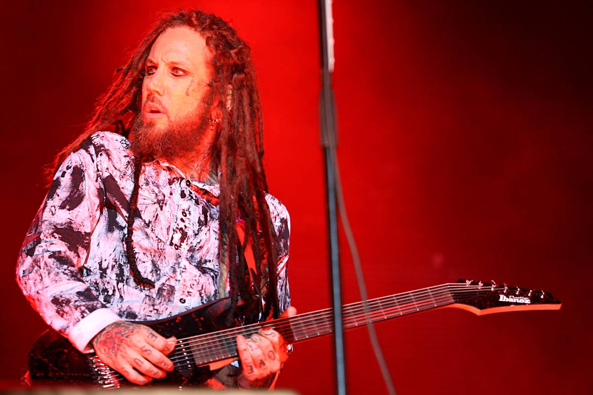 Korn guitarist Brian Welch playing in a red lit stage setting
