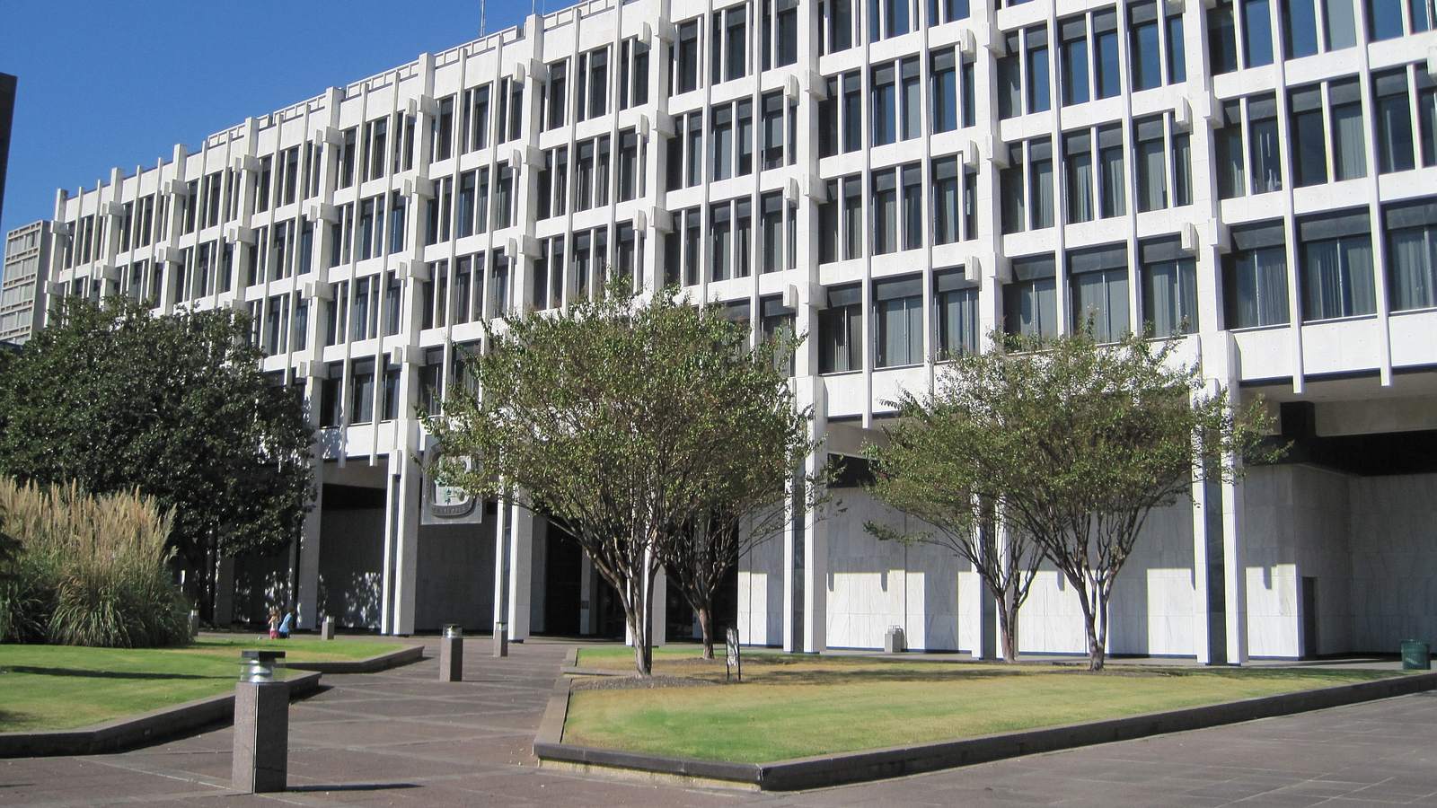 Memphis City Hall, a white modernist office block on Main Street, behind trees and a paved plaza