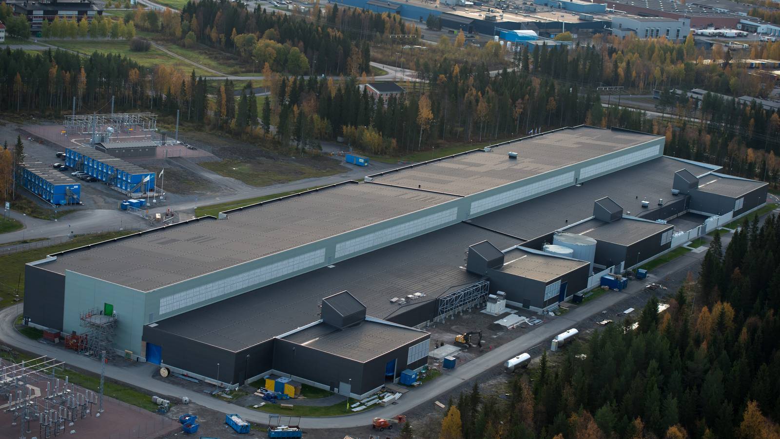 Aerial view of Meta's long grey data centre halls in Luleå, Sweden, surrounded by autumn forest