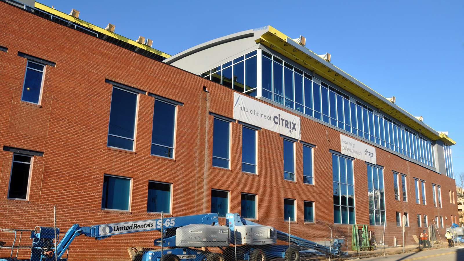A red brick office building under construction with a glass upper storey and a Future home of Citrix banner