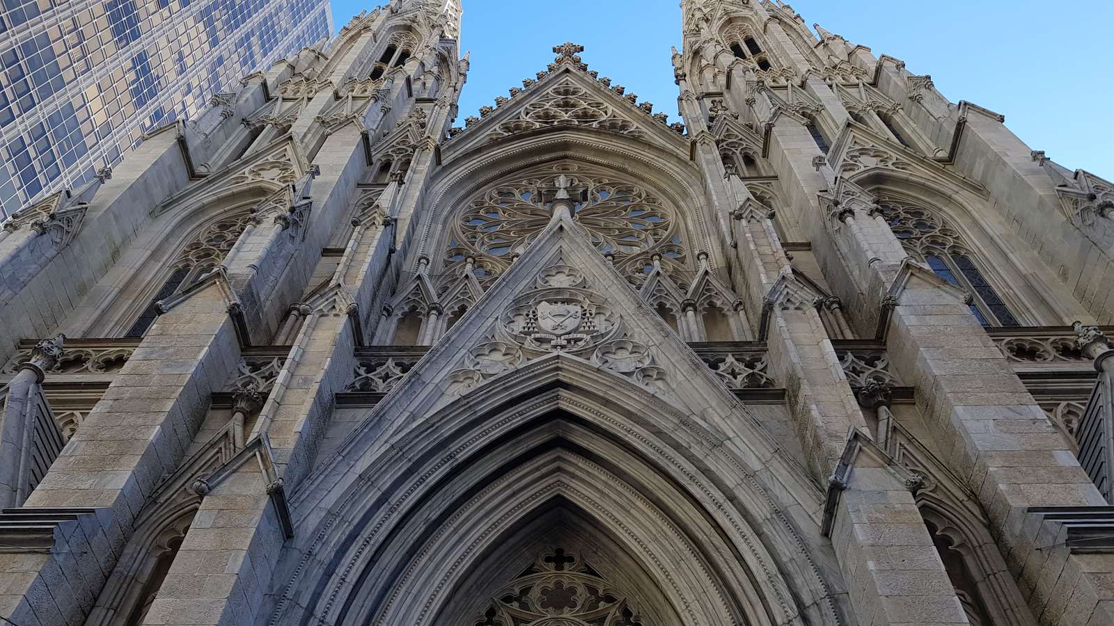 The Gothic spires and carved stone entrance of St Patrick's Cathedral in Manhattan against a blue sky