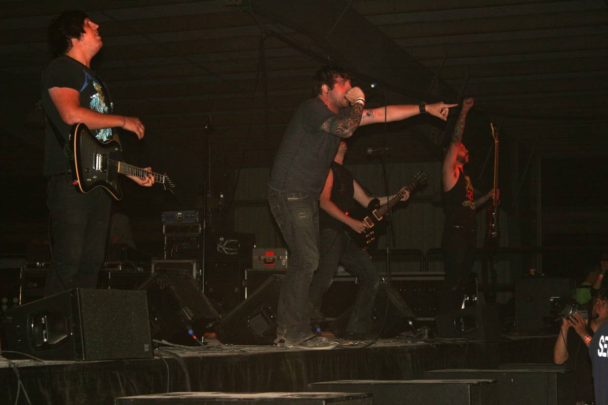 Norma Jean performing on a dark stage as the singer points out toward the crowd