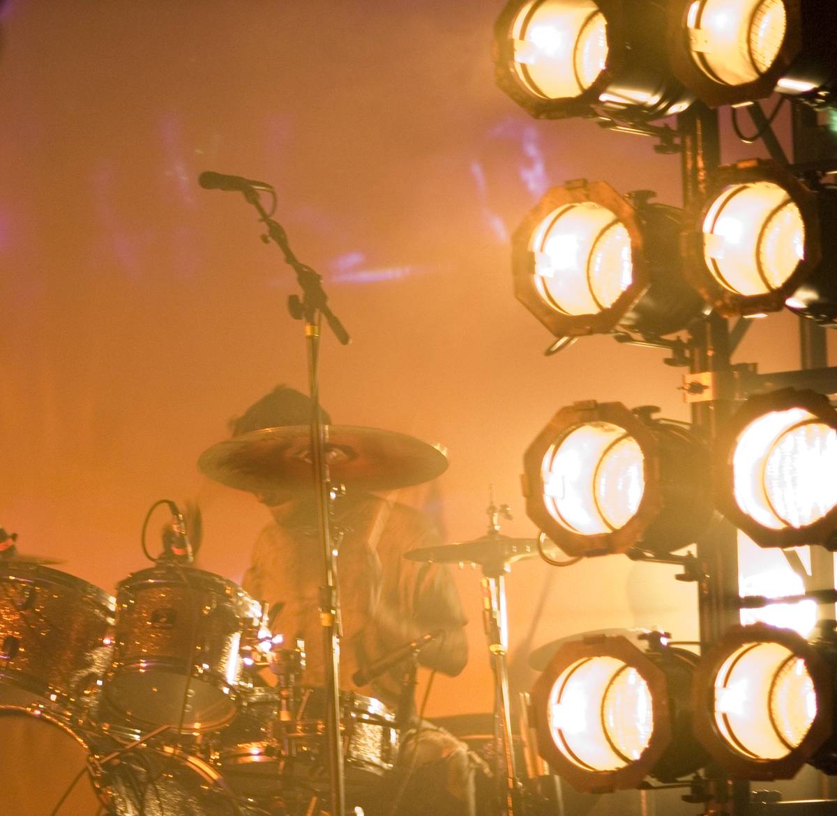 Norma Jean's drummer behind a kit lit in orange