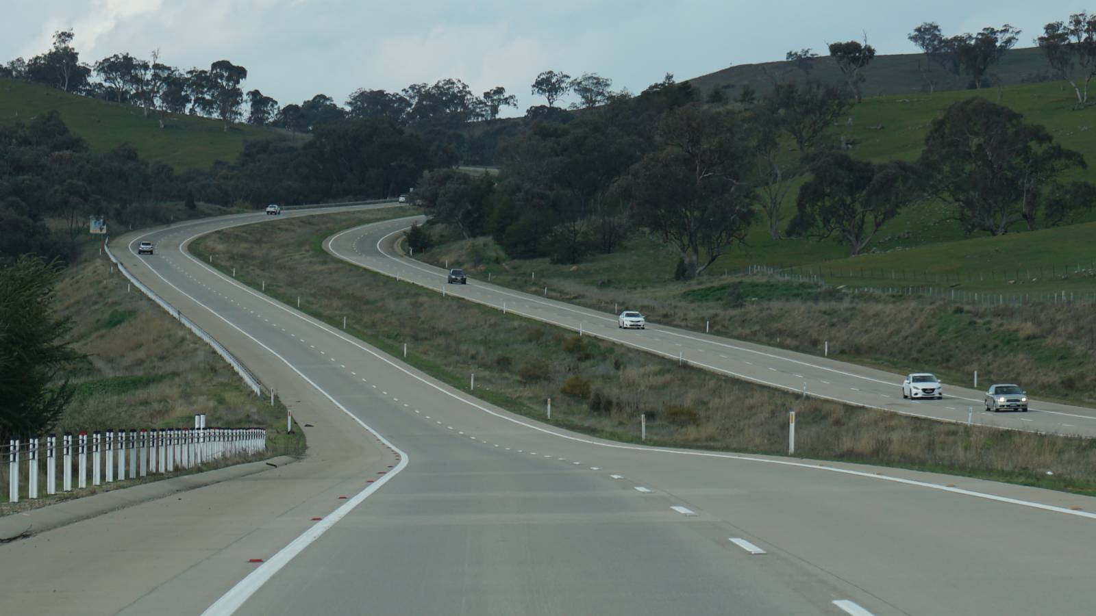 The divided Hume Highway curving through green hills and gum trees in southern New South Wales, with a few cars