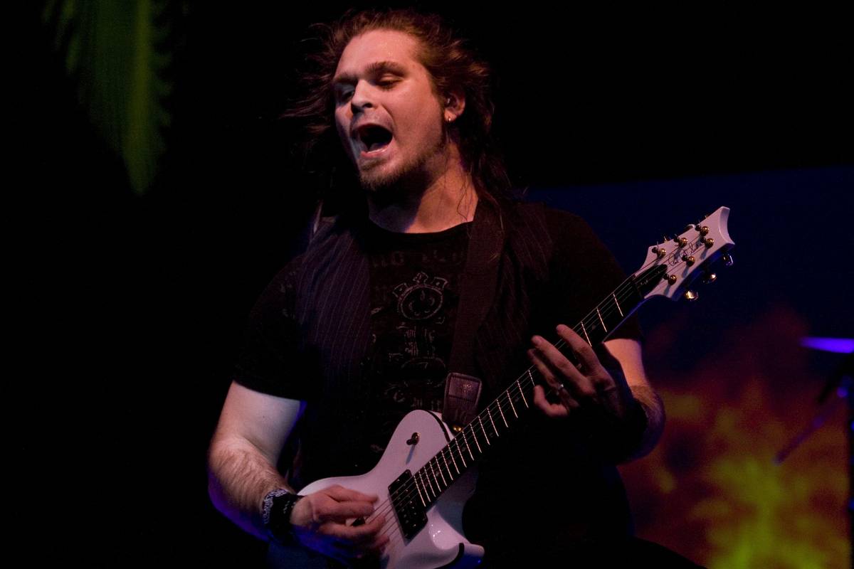 Pillar guitarist Noah Henson playing on a dark stage