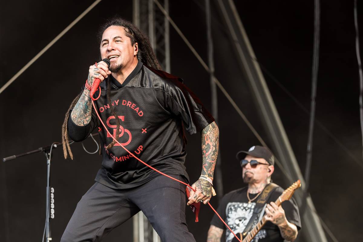 P.O.D. singer Sonny Sandoval singing with a guitarist behind him on an outdoor stage
