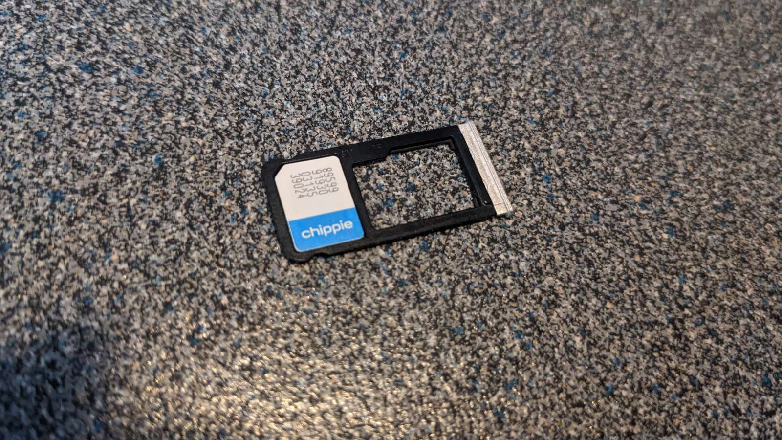 A Chippie nano SIM card sitting in a phone SIM tray on a speckled grey surface