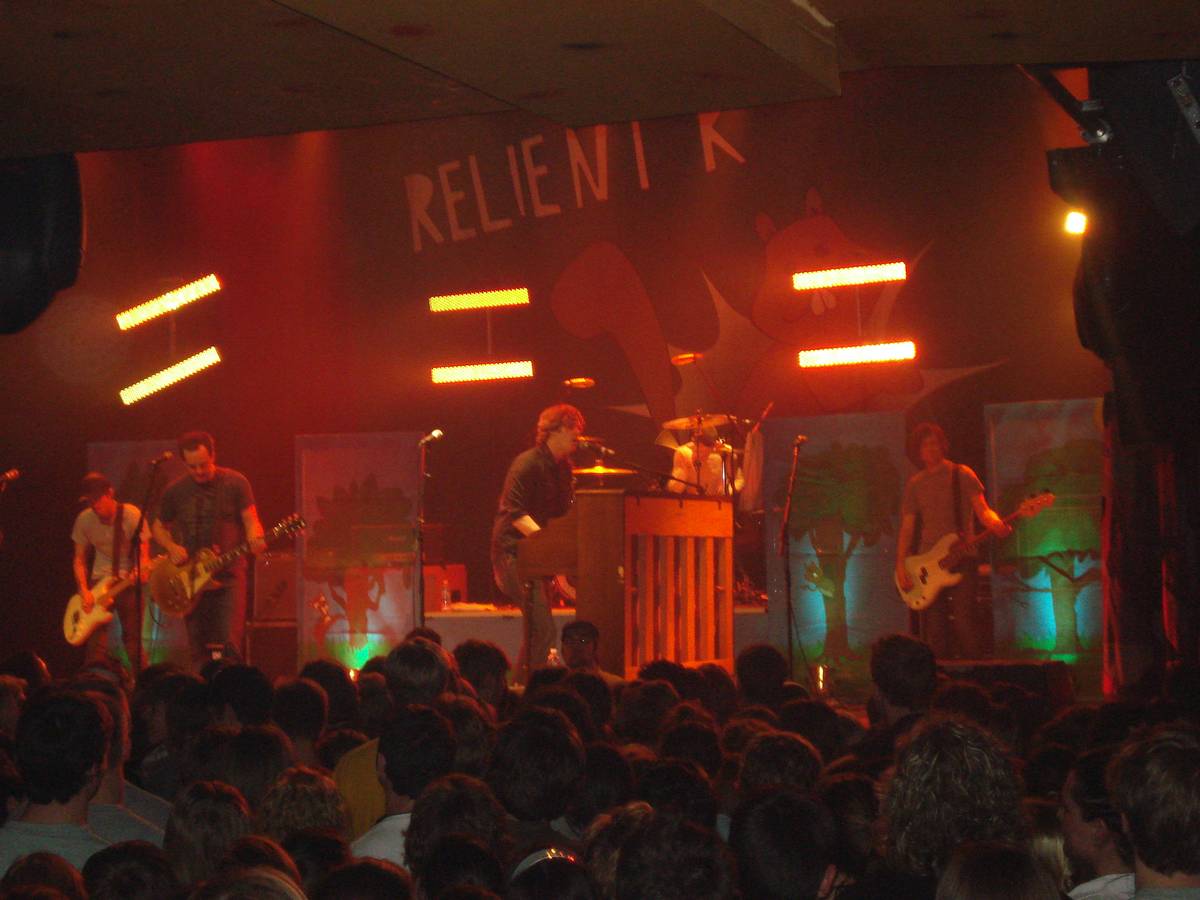 Relient K on stage under orange and red lights with a crowd in front