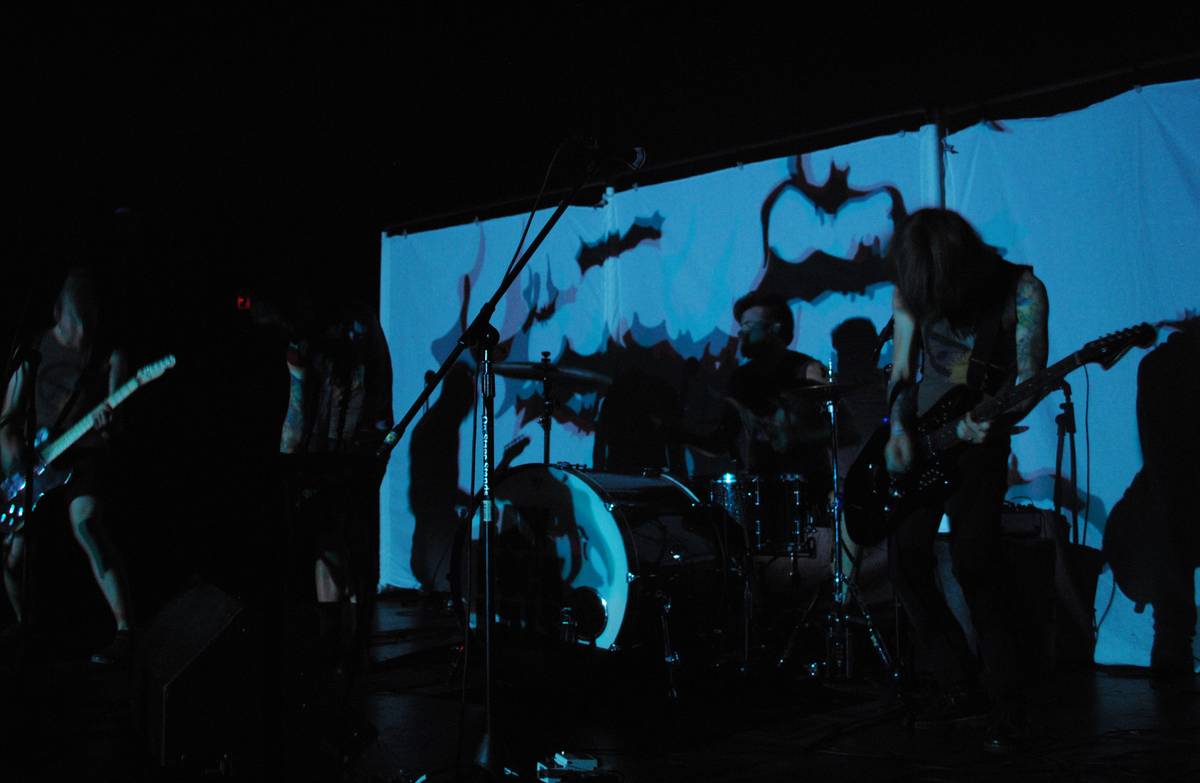 Showbread in silhouette against a bright projection screen