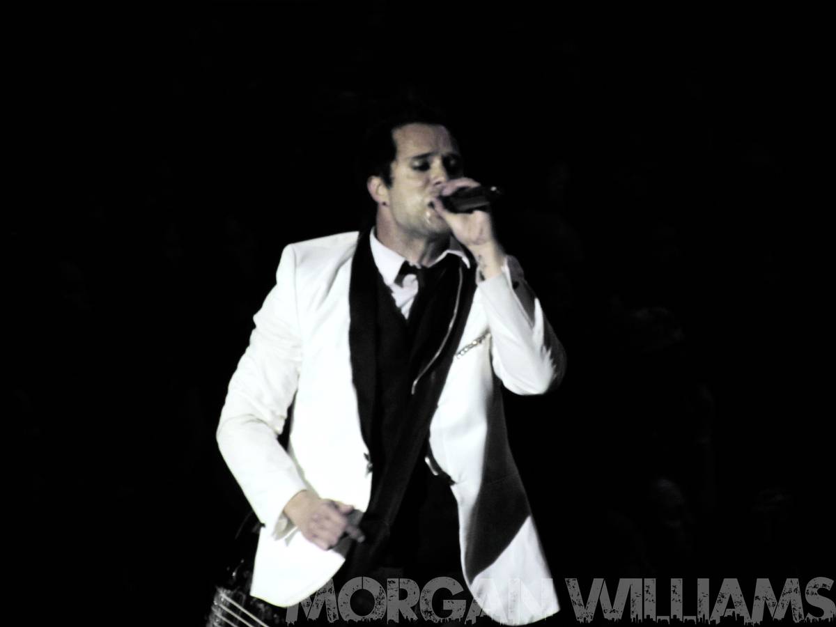 Skillet singer John Cooper in a white jacket singing on stage