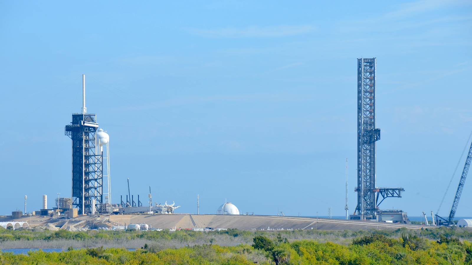 Two launch towers at Kennedy Pad 39A, Falcon on the left and the taller Starship tower on the right under a clear sky