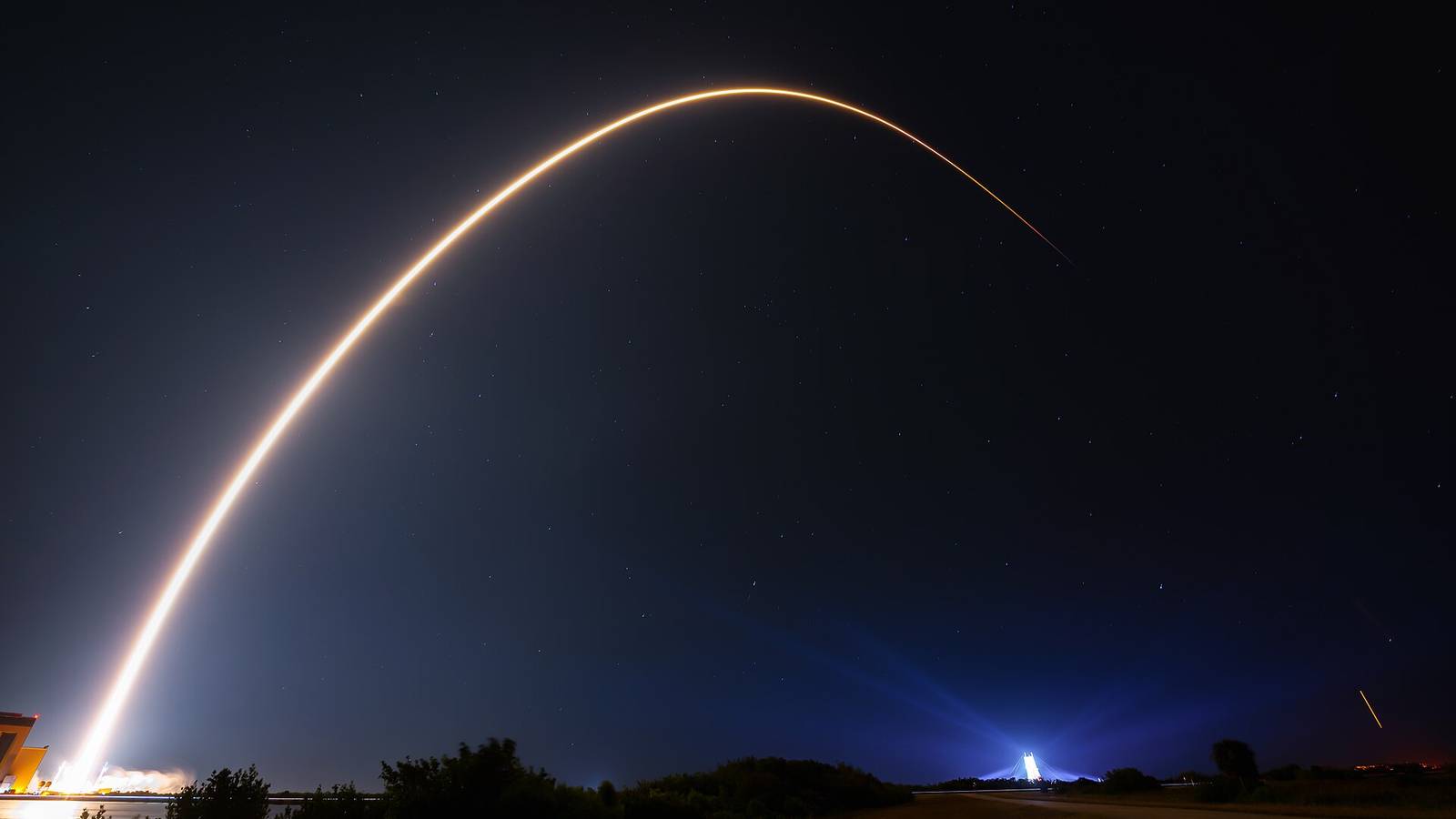 A long exposure of a Falcon 9 carrying Starlink satellites arcing into the night sky