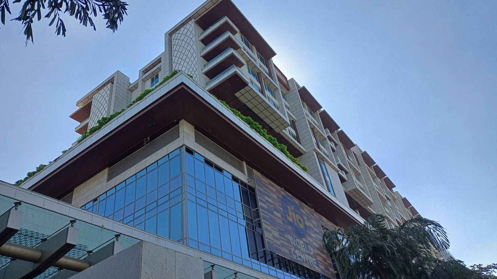 The terraced glass and stone Jio World Centre building in Mumbai seen from below against a clear sky