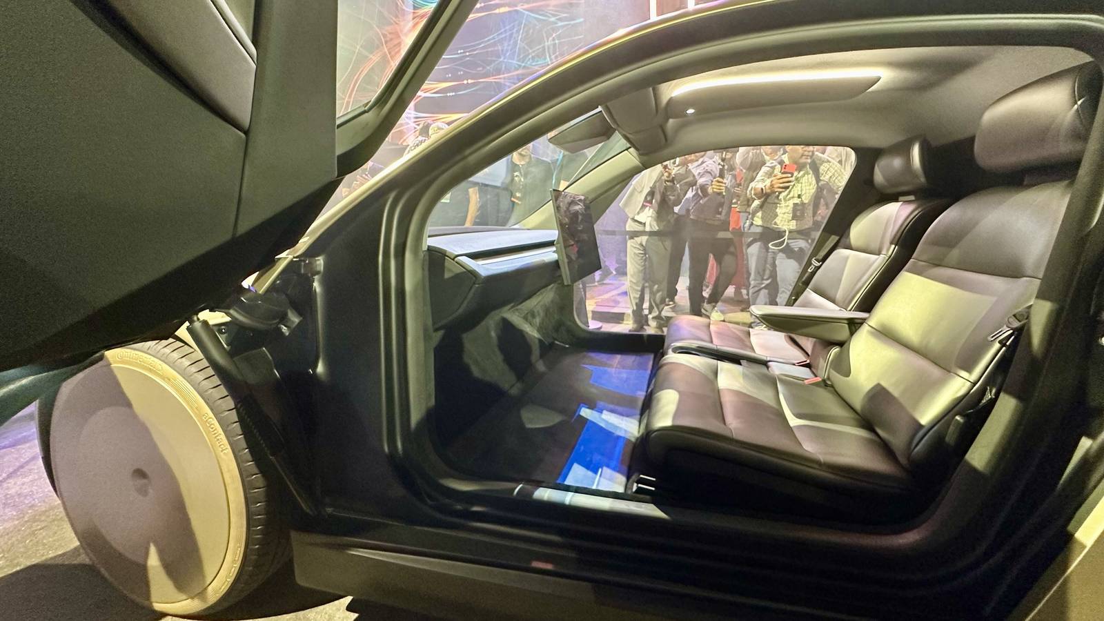 The inside of a Tesla Cybercab seen through its open door: two seats, a dashboard screen and no steering wheel or pedals
