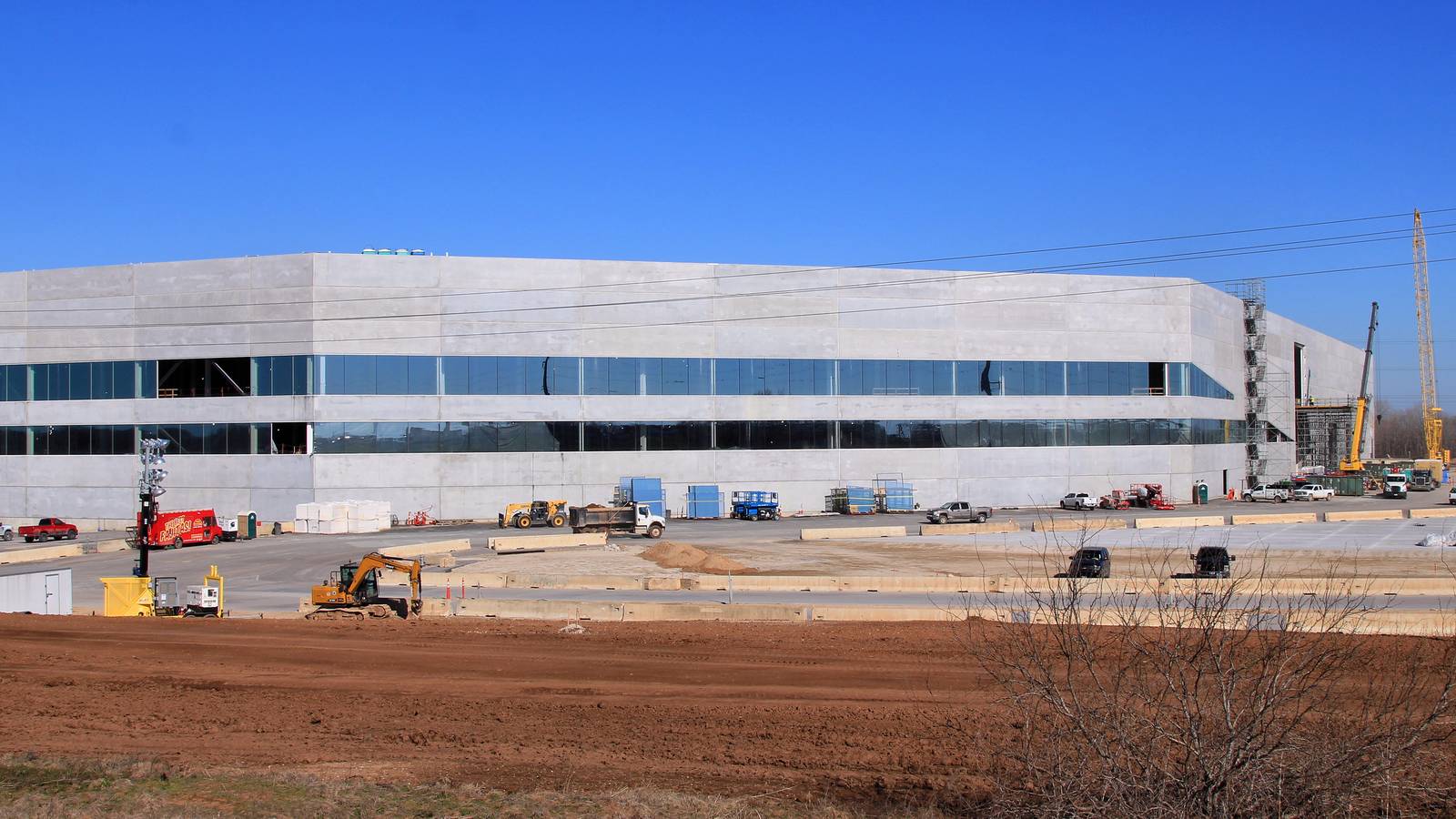 Tesla's Gigafactory Texas building under construction near Austin, with cranes and trucks on site