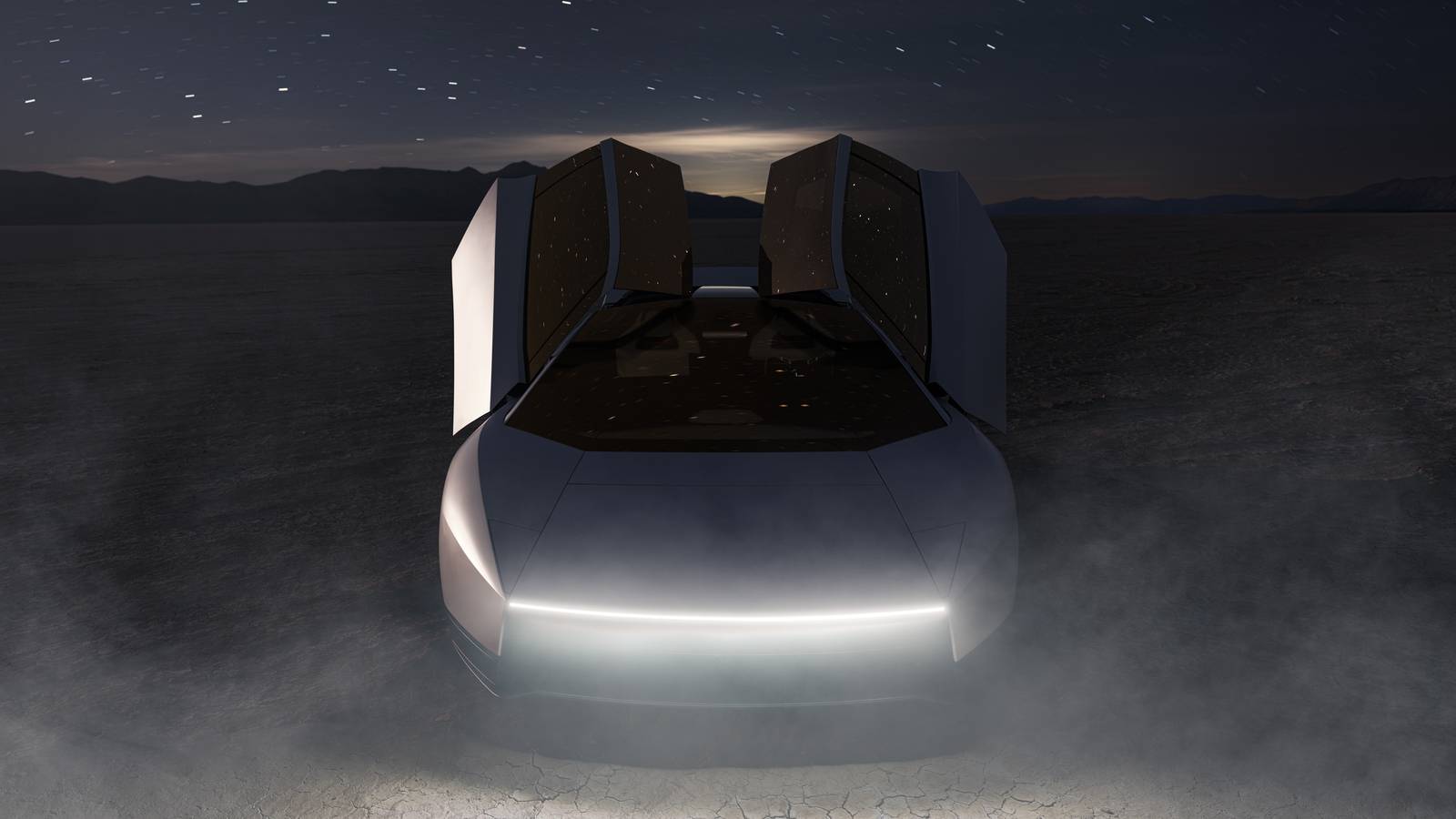 A white Tesla Roadster facing the camera at night on a dry lakebed, both doors raised under a starry sky