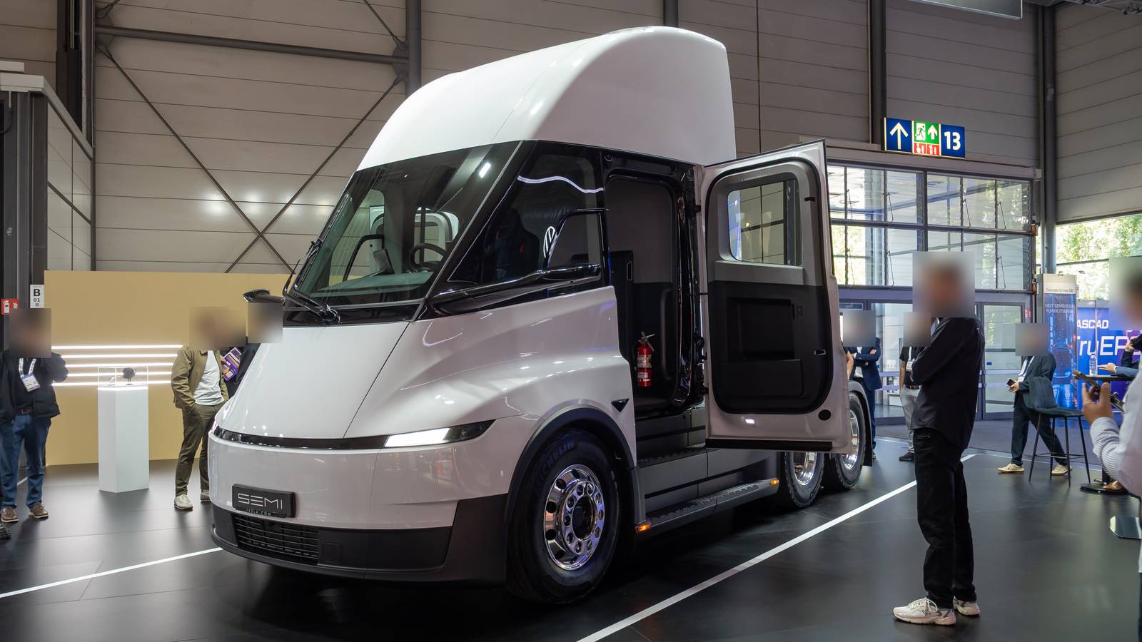 A white Tesla Semi on display at a truck show, its cab door open