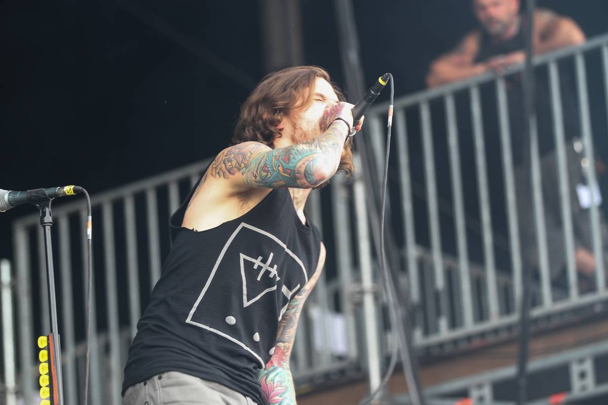 The Devil Wears Prada singer shouting into a microphone on an outdoor stage